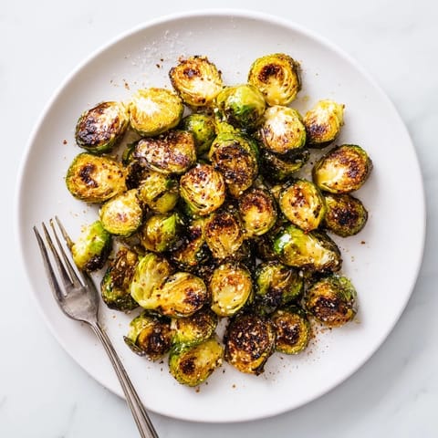 Roasted Brussels Sprouts paired with lemon wedges and parmesan on a rustic plate for a delicious vegetarian side.