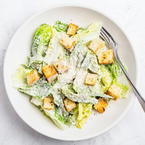 Freshly chopped romaine lettuce tossed in creamy Caesar salad dressing, topped with crunchy homemade croutons and grated Parmesan.