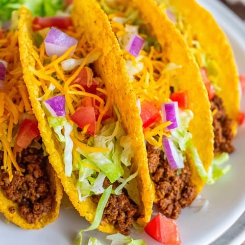 Golden crunchy shells filled with spicy beef, diced tomatoes, zesty salsa, and shredded cheese on a rustic table.