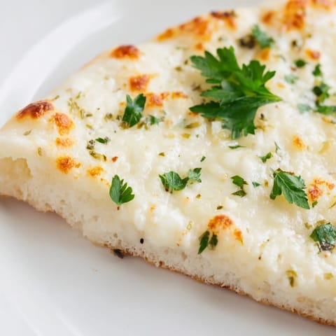 A close-up of a creamy garlic white pizza, highlighting the velvety sauce and fresh parsley garnish.  
