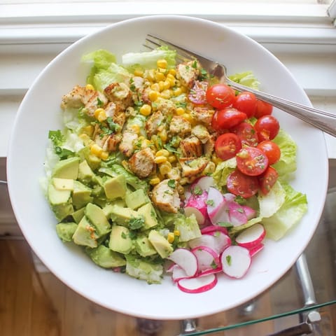 Freshly grilled chicken, charred corn, and creamy avocado tossed in a zesty lime dressing, making a vibrant Roasted Corn & Chicken Chopped Salad.