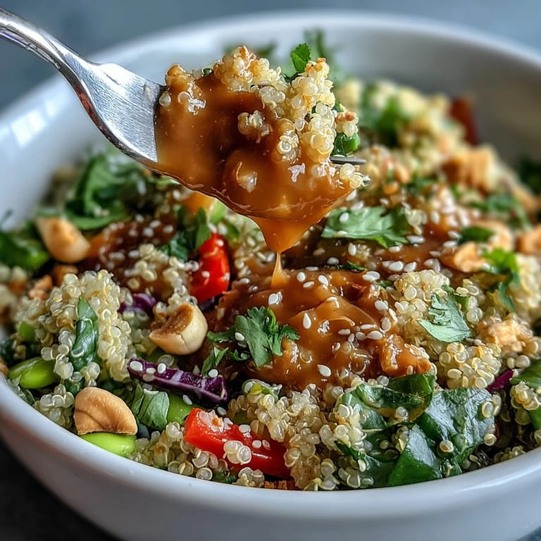 Fresh Thai-inspired coconut quinoa bowl loaded with crunchy vegetables, sesame seeds, and rich peanut dressing for flavor.