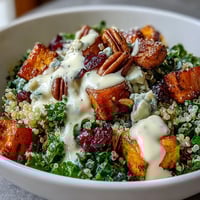 Harvest Kale Quinoa Bowl with roasted sweet potatoes, massaged kale, and zesty lemon tahini dressing in a rustic bowl.