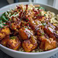 Spiced chicken and roasted sweet potatoes layered over fluffy quinoa in a vibrant Hot Honey Chicken Bowl.