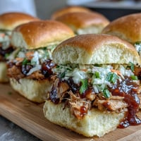 Juicy BBQ chicken sliders with tangy coleslaw piled high on soft slider buns, perfect for summer parties.  