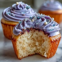 Fluffy Gemini birthday cupcakes adorned with a vibrant, two-toned buttercream swirl.